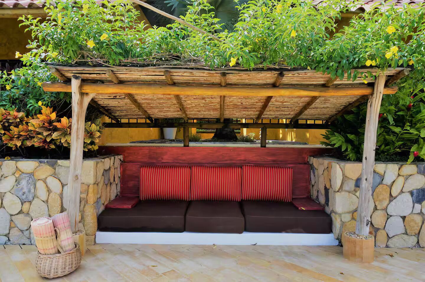 Ein überdachter Außenbereich mit Steinmauer und Holzpergola.