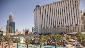 A large hotel with a pool area, palm trees, and a casino in the background.