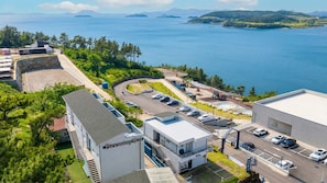 A coastal hotel with a parking lot, a swimming pool, and a view of the sea. - Yeosu Blooming Ocean View Family Pension (Yeosu)
