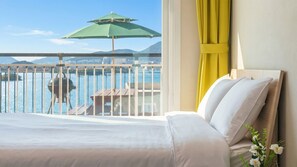 A hotel room with a balcony, a view of the water, a grill, and a table with an umbrella. - Yeosu Blooming Ocean View Family Pension (Yeosu)