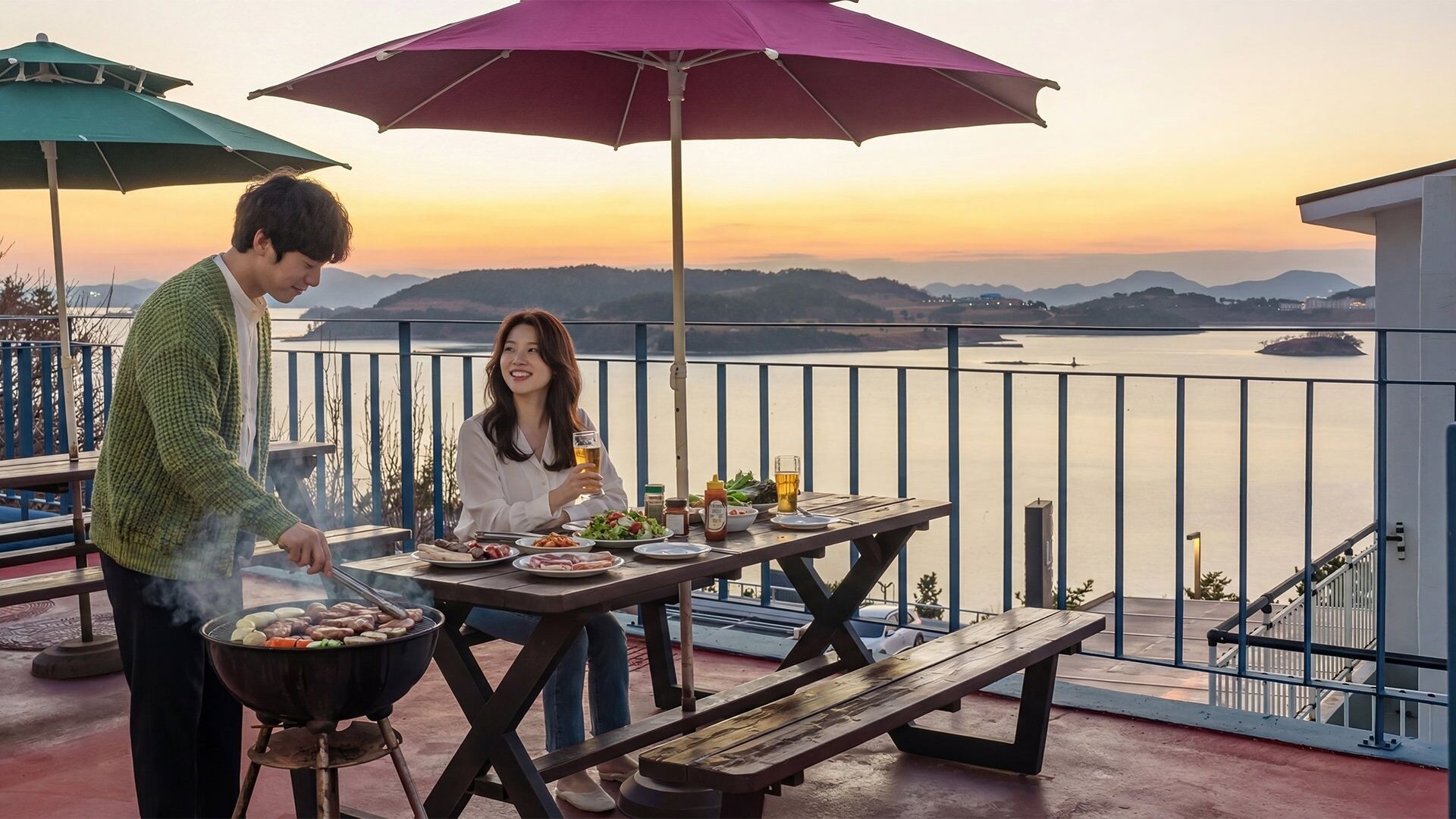 A couple dining outdoors with a view of a body of water and mountains at sunset.