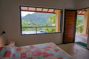 A bedroom with a large window offering a view of a mountainous landscape.