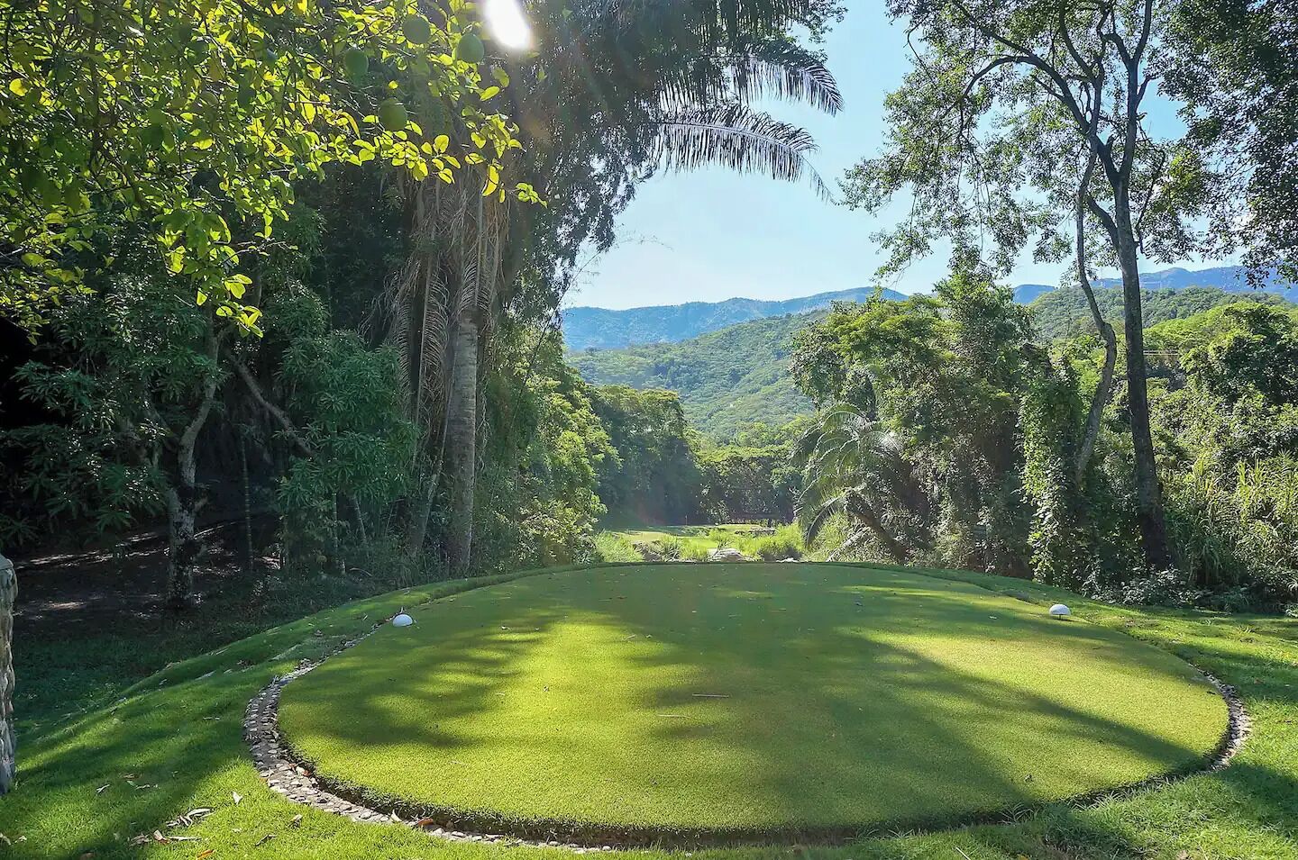 Un campo de golf bien cuidado con vistas despejadas del bosque circundante y colinas lejanas.