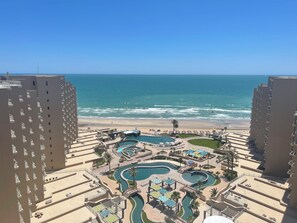 Um resort com várias piscinas, uma praia e edifícios altos.