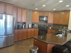 A modern kitchen with wooden cabinets, stainless steel appliances, a granite countertop, and a tiled backsplash. - Spacious 3-bedroom penthouse condo in marvelous Puerto Peñasco. (Puerto Peñasco)