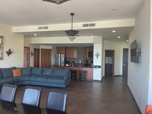 A spacious living area with a sofa and chairs, a kitchen with wooden cabinets, and a dining area with a table and chairs. - Spacious 3-bedroom penthouse condo in marvelous Puerto Peñasco. (Puerto Peñasco)