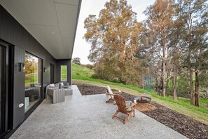 Un espace extérieur moderne aménagé avec un foyer, une table à manger et des chaises.