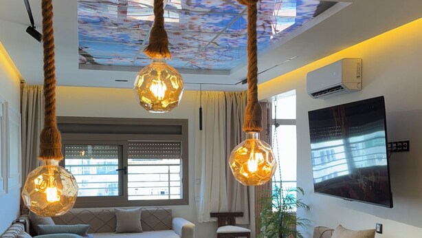 Een moderne woonkamer met een bank, een bijzettafeltje en hangende lichtkoorden.