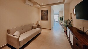 A modern hotel lobby with a sofa, a TV, and a wooden console. - OVATA TH-1/1 BR/Rooftop con Alberca/Zona Romántica (Puerto Vallarta)