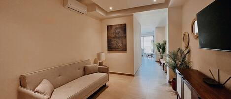 A modern hotel lobby with a sofa, a TV, and a wooden console.
