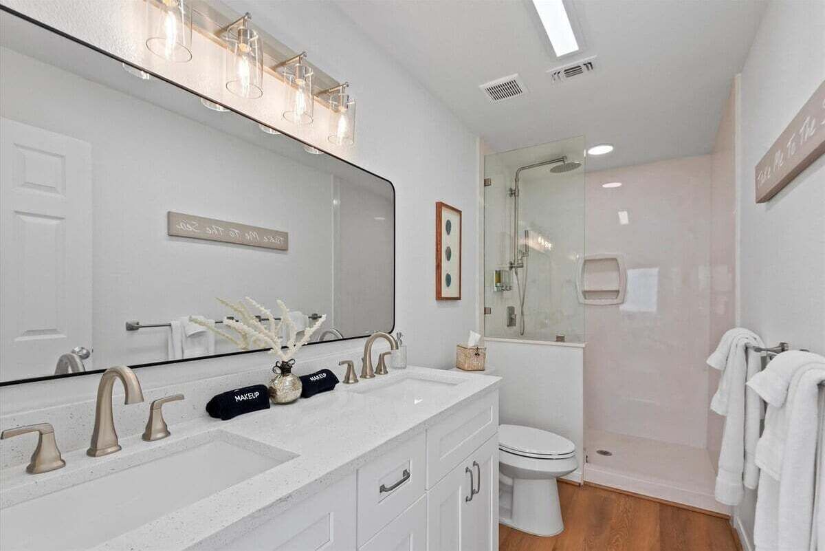 Une salle de bain moderne avec un grand miroir, deux lavabos et un espace douche.
