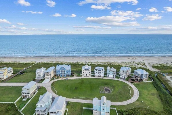 A coastal residential area with multiple houses and a beach in the background. - Beachfront + Hot Tub | Game Room + Pets | Sleep 18 (Galveston)