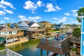 A waterfront property with multiple decks, a dock, and a canal. - Galveston Canal Home | Large Deck | Sleeps 14 (Galveston)