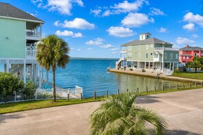 A waterfront property with a balcony, a pool, and a view of the water. - Galveston Canal Home | Large Deck | Sleeps 14 (Galveston)