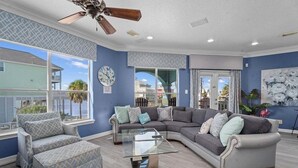 A living room with a sectional sofa, a glass coffee table, and a ceiling fan.