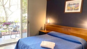 A bedroom with a large bed, a nightstand, a lamp, and a view of the outdoors. - Hotel Praja Mare (Praia a Mare)