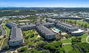 A resort with multiple buildings, a central pool, and surrounding greenery. - The Pool Resort Kingscliff - One Bedroom (4104) with ocean views - Holiday Management Co. (Tweed)