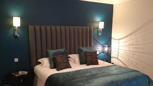 A bedroom with a large bed, two wall-mounted lights, and a dark headboard. - Fishmore Hall Hotel and Boutique Spa (Ludlow)