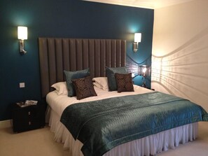 A bedroom with a large bed, two wall-mounted lights, and a dark headboard. - Fishmore Hall Hotel and Boutique Spa (Ludlow)