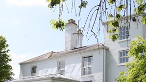 A white building with a large glass conservatory, multiple windows, and a well-maintained garden. - Fishmore Hall Hotel and Boutique Spa (Ludlow)