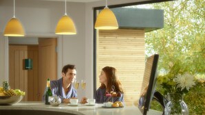 A modern kitchen with a wooden door, a fruit bowl, a bottle of champagne, and a vase with flowers. - Fishmore Hall Hotel and Boutique Spa (Ludlow)