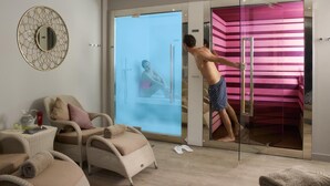 A modern bathroom with a glass shower enclosure, a large mirror, and a seating area with a chair and a small table. - Fishmore Hall Hotel and Boutique Spa (Ludlow)