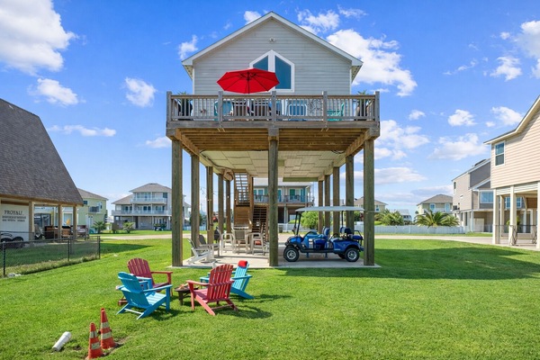 Exterior view of elevated Galveston beach house with spacious yard and outdoor seating, perfect for family beach vacations near the Gulf Coast.