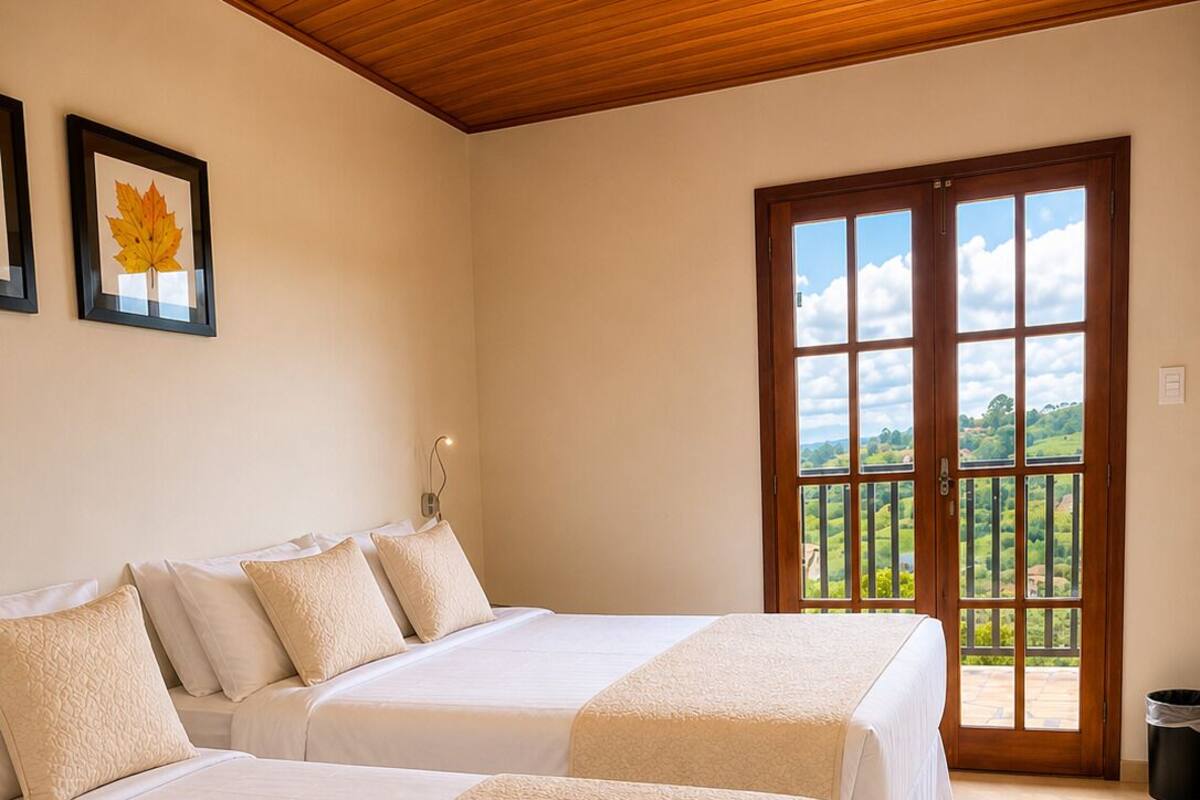 Ein Hotelzimmer mit zwei Betten, einer Holzbalkendecke, einem gerahmten Blatt an der Wand und einem großen Fenster mit Aussicht.