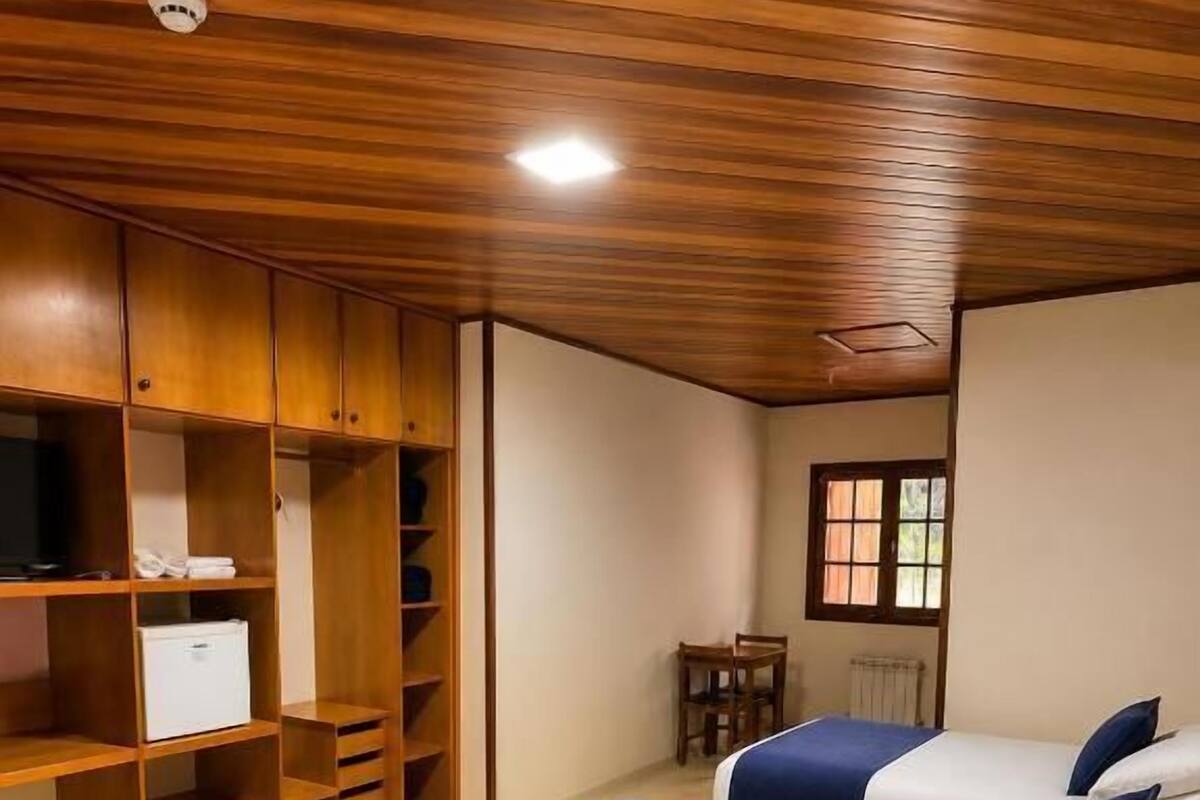 Ein Zimmer mit zwei Betten, Holzschränken, einem kleinen Tisch und einem Fenster.