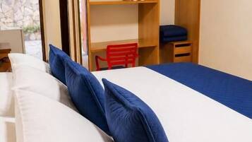 A bedroom with a bed, pillows, a wooden wardrobe, a chair, and a television.