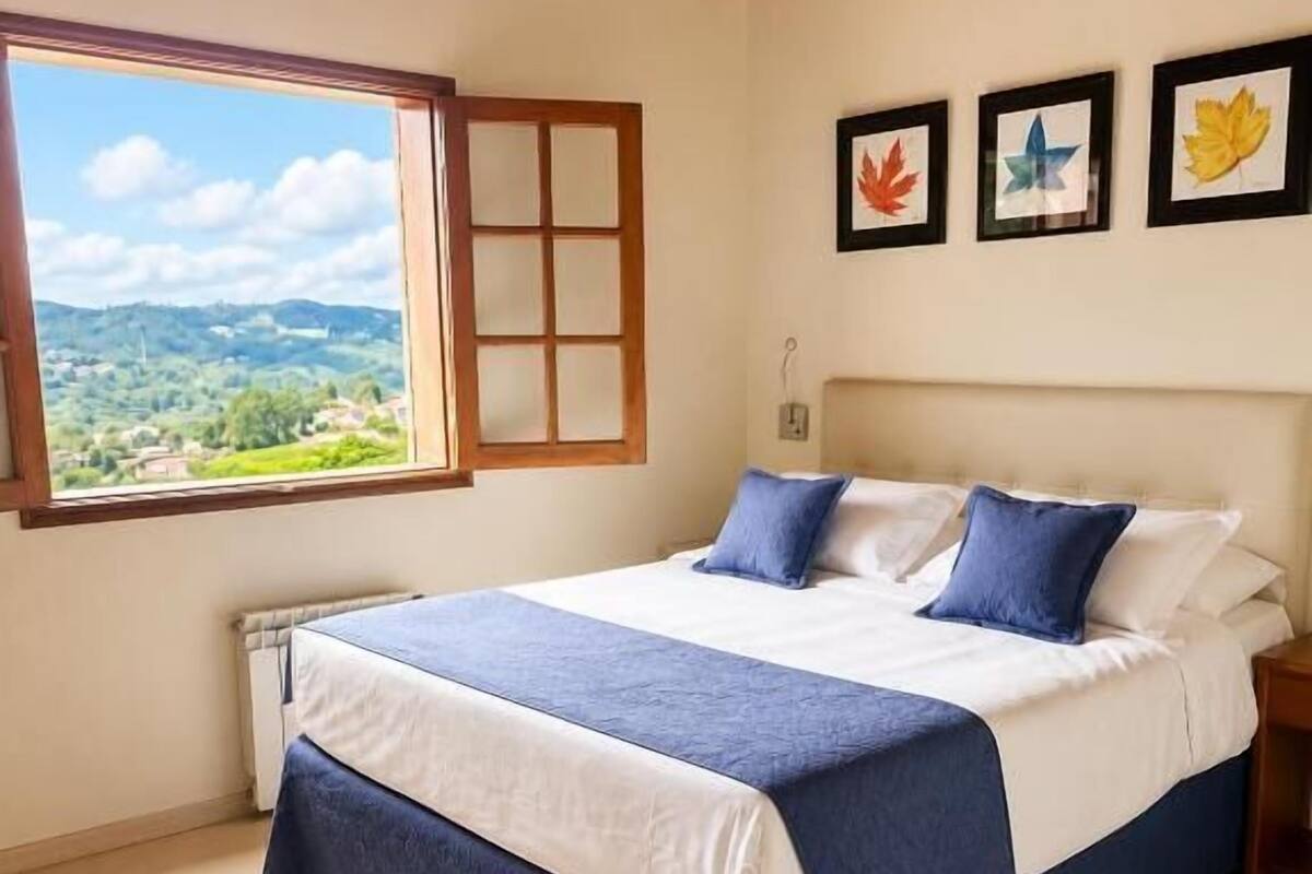 Ein Schlafzimmer mit einem Bett, einem Fenster und gerahmten Bildern an der Wand.
