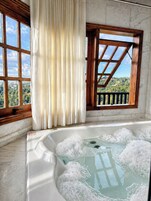Una habitación con hidromasaje, ventanas amplias y vistas al paisaje.
