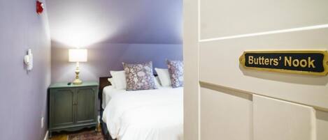 Un dormitorio con una cama, una mesita de noche, una lámpara y un letrero que dice 'Butters' Nook'.