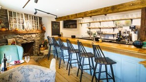 A cozy bar area with a stone fireplace, bar stools, and a wooden ceiling. - Green Trails Inn (Brookfield)