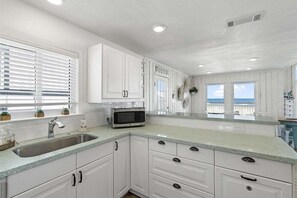 Bright kitchen with modern finishes and Gulf views, allowing guests to enjoy the coastal scenery while preparing meals. - Beachfront + Hot Tub | Putt-Putt | Pet-Friendly (Galveston)