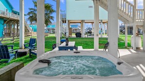 A hot tub under a covered area with chairs and a view of a building. - Walk to Beach with Expansive Deck & Hot Tub | Sleeps 12 (Port Bolivar)