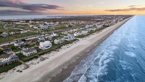 An aerial view of a coastal residential area with houses along the beach, a road, and a view of the ocean. - Beachview | Fire Pit | Cargo Lift | Pet-Friendly | Steps to Shore (Galveston)