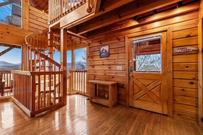 A wooden cabin interior with a spiral staircase, a fireplace, and a cabin sign. - Smoky Mountain Views | Hot Tub | Game Room | Sleeps 12 (Sevierville)