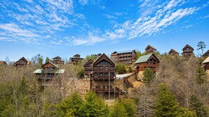 Un grupo de cabañas de madera con balcones, rodeadas de árboles, bajo un cielo despejado.