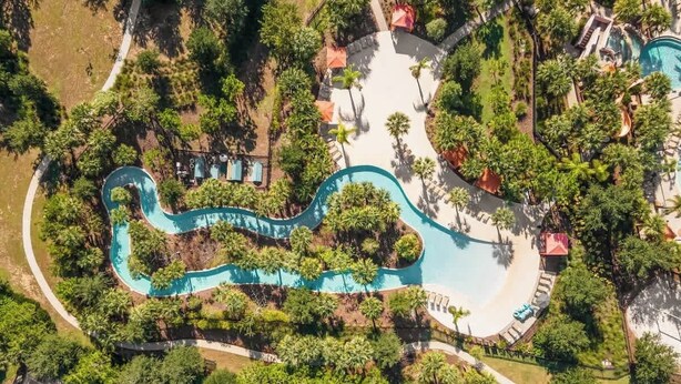 An aerial view of a resort with a winding pool, surrounded by lush greenery and palm trees. - Chic Family Home, Mario Bros, Harry Potter & Pool (Davenport)