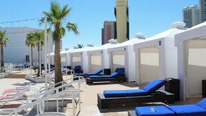 Área de piscina en la azotea con tumbonas, palmeras y vistas al horizonte de la ciudad.