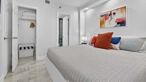 A bedroom with a bed, a closet, a bathroom, and a painting on the wall. - 6165 CD Unit 3302 Enclave Urban Escape (Orlando)