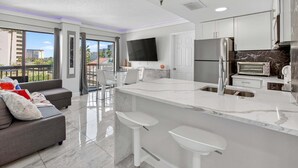 A modern kitchen with a large island, a dining area, and a sofa. - 6165 CD Unit 3302 Enclave Urban Escape (Orlando)