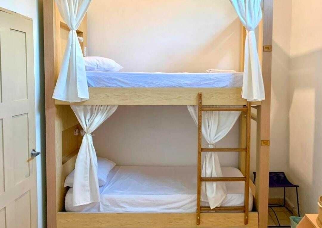 A bunk bed with a ladder, white bedding, and curtains.