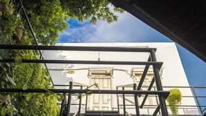 Una escalera que conduce a un edificio de fachada blanca y una puerta con un ventanal encima.