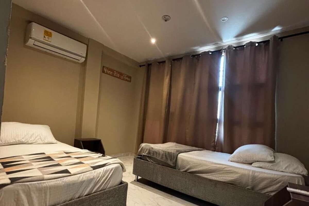 Habitación de hotel con dos camas, piso de mármol, unidad de aire acondicionado y un letrero en la pared.