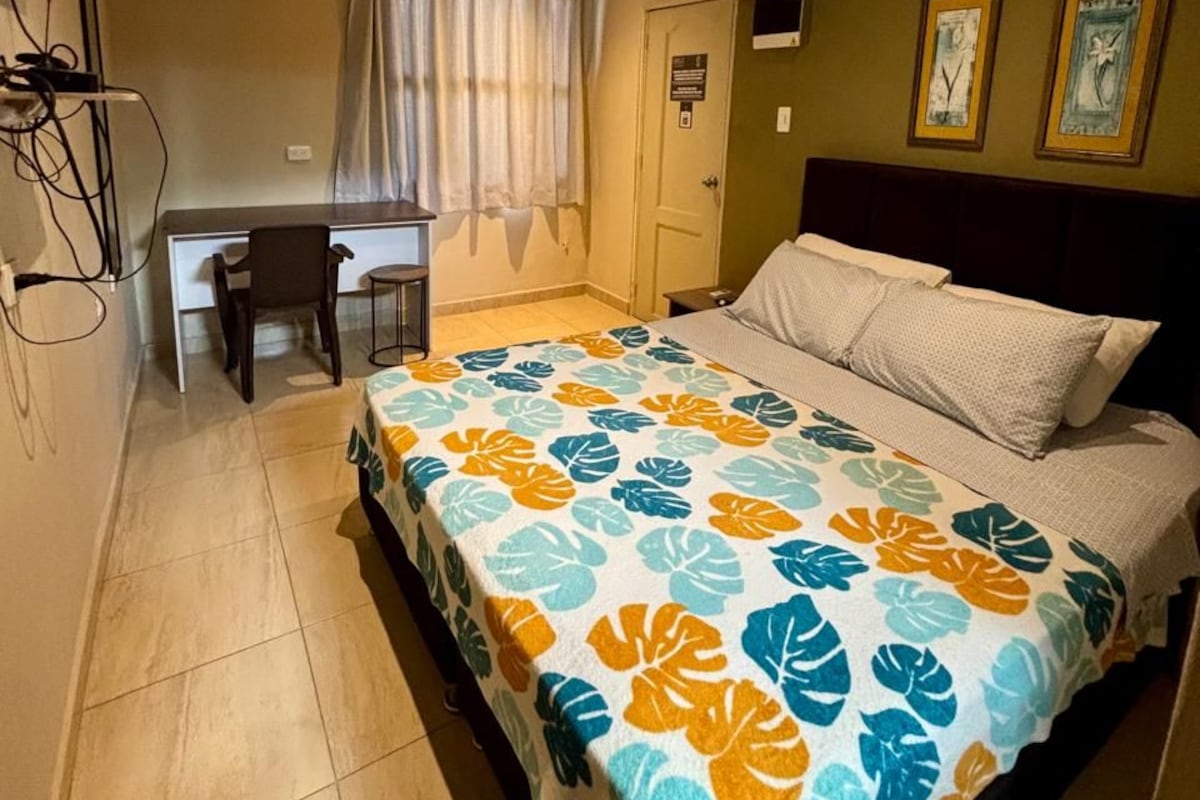 Un dormitorio con una cama, un escritorio y una silla.