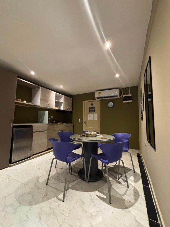A compact kitchen with modern appliances, a dining area with a round table and four chairs, and a wall-mounted air conditioning unit. - Musa Paradisaca Lodging (Santa Marta)