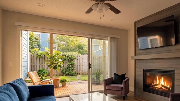 A living room with a fireplace, a TV mounted above it, and a sliding glass door leading to a patio with outdoor furniture. - Inside Wilmington’s Calmest In-Town Stay with Garden Patio! (Wilmington)