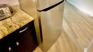 A stainless steel LG refrigerator in a kitchen with a granite countertop, dark cabinetry, and a light wooden floor. - Inside Wilmington’s Calmest In-Town Stay with Garden Patio! (Wilmington)